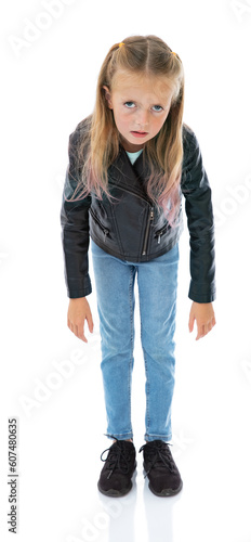 Full-length portrait of very exhausted eight year old girl looks at camera, isolated on white background. Frustrated girl in black leather jacket and blue jeans posing in studio.