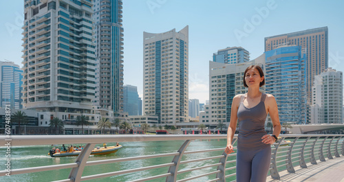 City Running - asian woman runner , Dubai marina urban scene in background. Female athlete, fitness athlete jogging training, living healthy lifestyle.