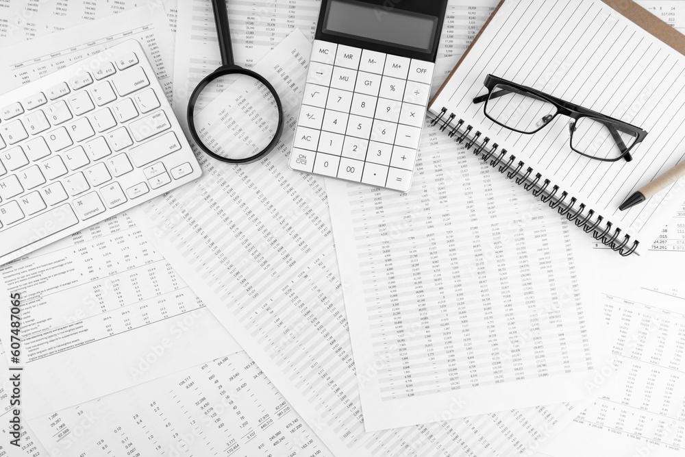 Calculator, keyboard, magnifying glass, eye glasses lying on financial statement. Top view. Calculator, keyboard, magnifying glass, eye glasses lying on financial statement. Top view.