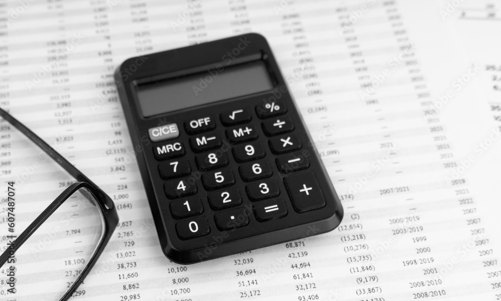 Calculator, keyboard, magnifying glass, eye glasses lying on financial documents. Top view. Calculator, keyboard, magnifying glass, eye glasses lying on financial documents. Top view.