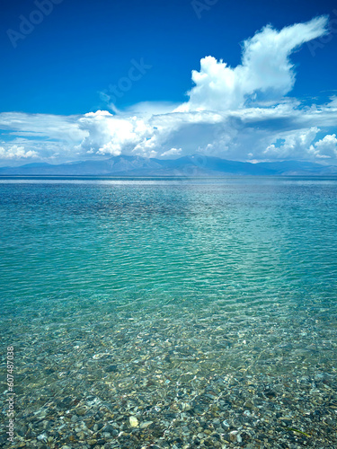 Panoramic view of a beautiful pebble beach  with turquoise sea and partly cloudy sky. Scenic landscape image.