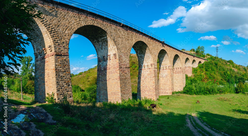 Stone railway ancient arch bridge over the green valley