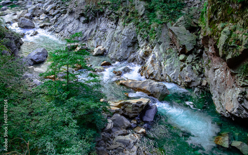 Panorama con torrente che scorre tra rocce, alberi e pareti rocciose, in estate.  Acqua che scorre lungo il fiume. Parco Nazionale della Val Grande. Piemonte, Italia. Alpi Italia. Alpi italiane.  photo