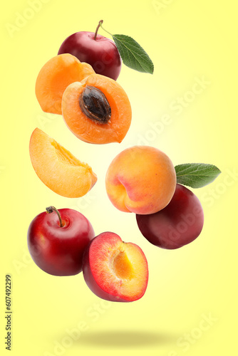 Flying apricots and plums on yellow background