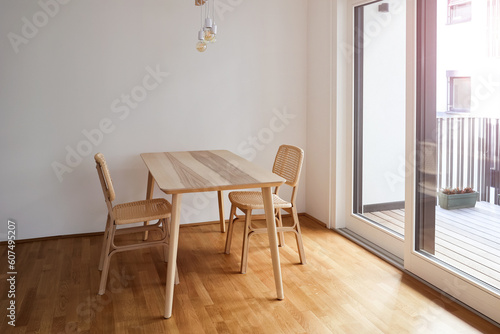 Wooden dining table with wicker chairs in light room