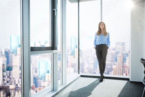 Thinking mid aged professional woman wearing business casual and standing in a modern office © gzorgz