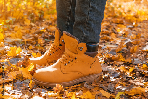 A man in red shoes walks through the autumn forest. Orange shoes on yellow dry fallen leaves. Rest, relaxation in the autumn forest. Autumn concept of walking through forest. Recreation and travel.