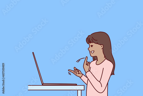 Silent teenage girl using laptop and sign language making video call to friends or school teacher for distance learning. Silent child gesturing standing near computer while learning to communicate