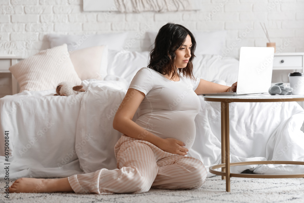 Young pregnant woman working with laptop in bedroom Young pregnant woman working with laptop in bedroom