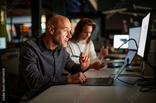 Businesswoman and businessman sitting together at computers and working at the office