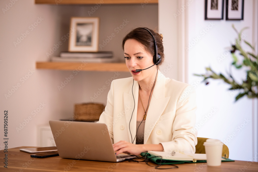 Confident woman with headshet and laptop working at home Confident woman with headshet and laptop working at home