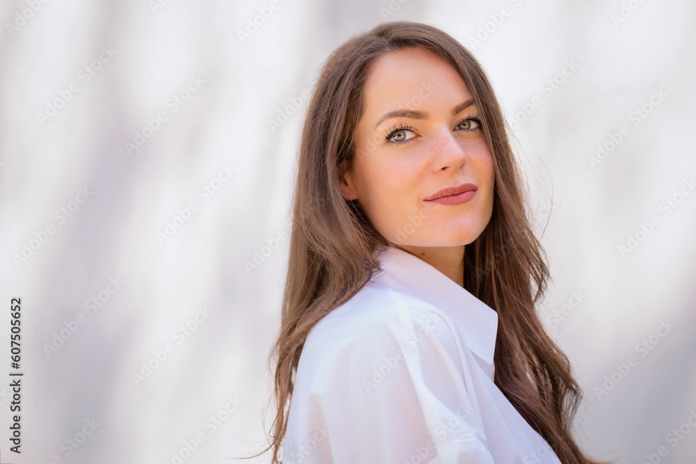 Beautiful young woman with brunette hair and blue eyes smiling against the sun Beautiful young woman with brunette hair and blue eyes smiling against the sun