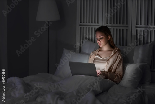 Young woman using laptop in bedroom at night