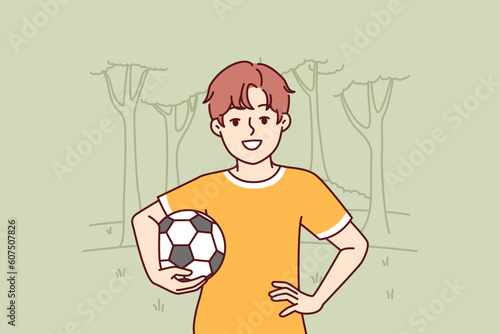 Little boy with soccer ball enjoys outdoor recreation and with smile looks at screen. Boy pupil elementary school, dreams of becoming professional football player and training in park to play soccer