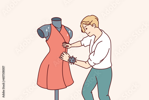 Man fashion designer sews dress fixed on mannequin preparing women outfit for Paris haute couture week. Professional fashion designer makes exclusive elegant clothes for girls to order