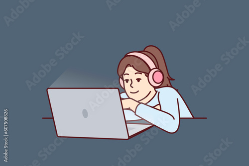 Little girl in headphones uses laptop watching children series or internet show for schoolchildren. Concept children internet addiction and need for restrictions in use of gadgets for children
