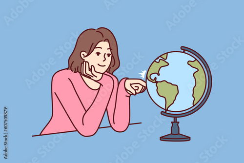 Woman dreams of traveling world looking at globe with planet earth and continents. Girl dreams of being tourist and going on trip to different countries and parts of world with distinctive culture