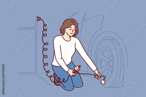 Woman is repairing car wheel using pump to pump air into tires and go on road trip. Independent young girl auto mechanic in garage inflates wheels of car performing vehicle maintenance.