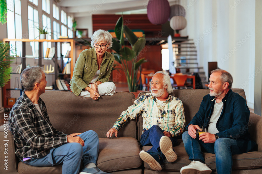 Four senior people having conversation while resting in living room Four senior people having conversation while resting in living room