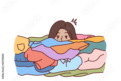 Face of woman near dirty clothes in need of washing with colored laundry detergent. Girl housewife or maid drowns in dirty linen due to overwork and overload with household chores.