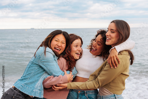 Reunited young women hugging on beach