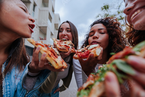 Four happy female friends enjoying street food together