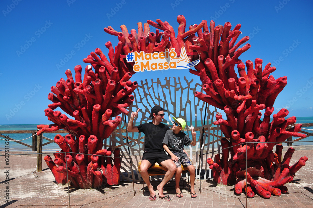 turistas pai e filho  na decoração de corais Maceió é massa  - obrazy, fototapety, plakaty 