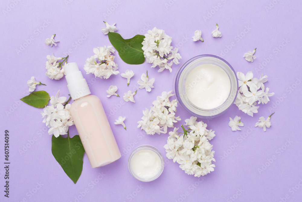 Composition with cosmetic bottles and flowers on color background, top view Composition with cosmetic bottles and flowers on color background, top view