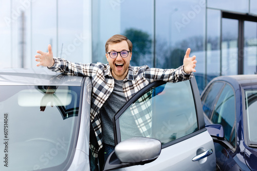 Great Car. Cheerful guy standing near auto, gesturing thumbs up buying vehicle in dealership center