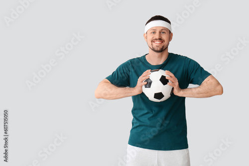 Happy man with soccer ball on light background © Pixel-Shot