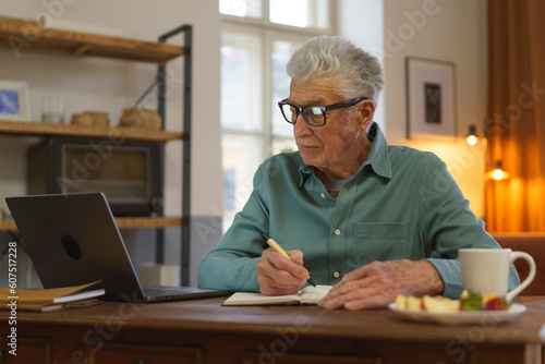 Senior man writing notes in his diary.
