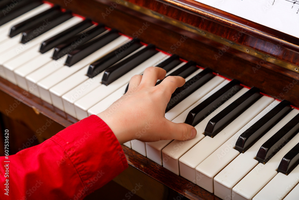 Fototapeta premium A child learns to play the piano in the lessons at a music school with a teacher.