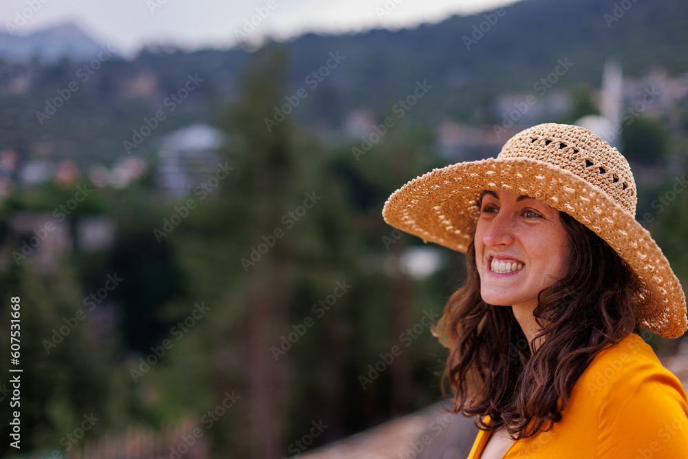 portrait of a beautiful young happy girl in a straw hat. The girl smiles and enjoys outdoor recreation.
