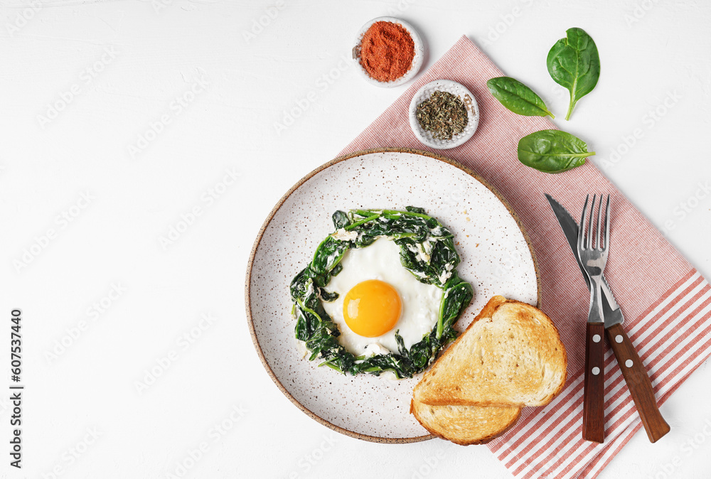 Fried eggs with fresh spinach and creamcheese on a plate on napkin on the white background, top view, copy space Fried eggs with fresh spinach and creamcheese on a plate on napkin on the white background, top view, copy space
