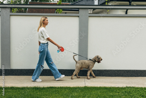 Side view of a blond woman taking the dog for a walk.