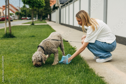 A responsible woman picks up dog waste on the grass photo