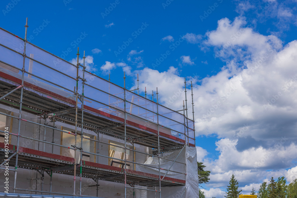 View of construction site fenced with scaffold with house under construction. Sweden.