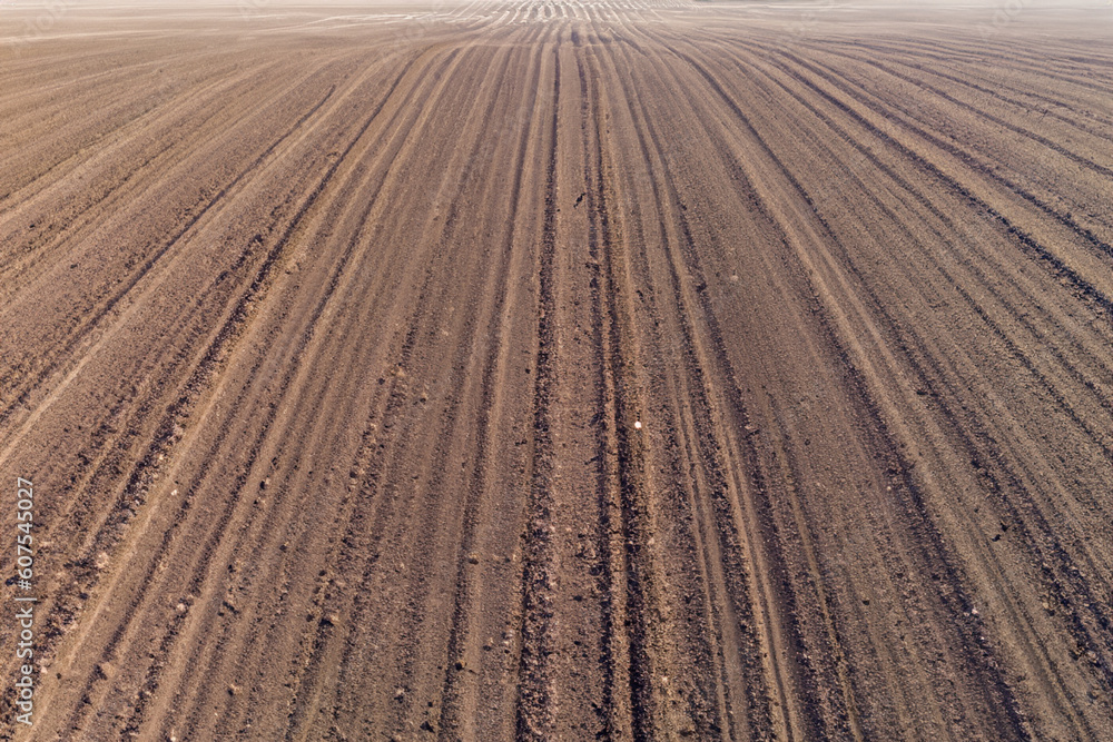 Aerial view ; Rows of soil before planting. Furrows row pattern in a plowed field prepared for planting crops in spring. Aerial view of land prepared for planting and cultivating the crop. Aerial view ; Rows of soil before planting. Furrows row pattern in a plowed field prepared for planting crops in spring. Aerial view of land prepared for planting and cultivating the crop.