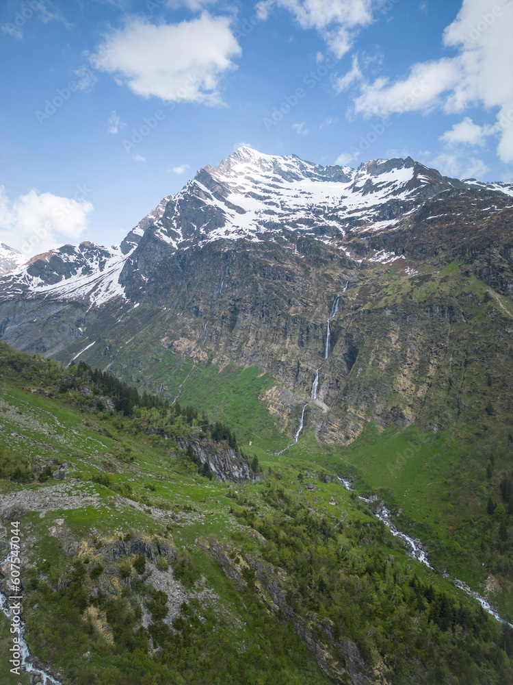 Sommer in den Alpen mit grünen Wiesen, Wasserfällen und Gletschern