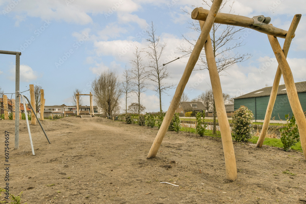 Fototapeta premium an outdoor play area with swings and wooden poles in the fore - image is taken from below, it's blue sky