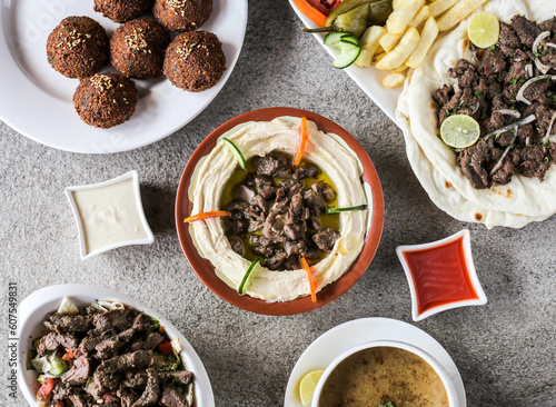 Assorted arabic food falafel, lamb shawarma platter, lentil soup, lamb hummus laham, beef fattoush bil laham served in dish isolated on background top view of Arabic fast food photo