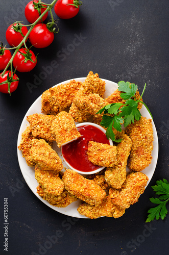 Delicious Crispy Fried Breaded Chicken Breast Strips with Ketchup on Dark Background