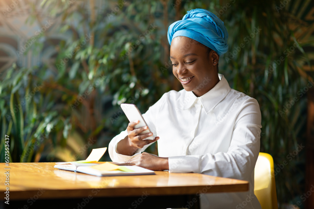 Fototapeta premium Pretty young black woman SMM manager sitting at cafe