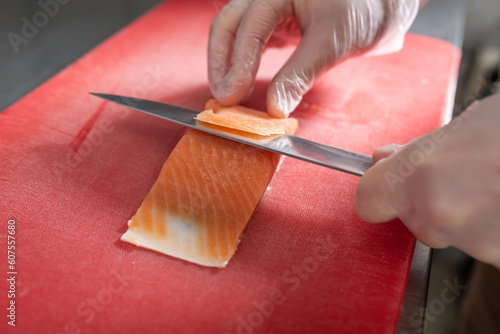 Cutting slices of red fish, for making rolls.