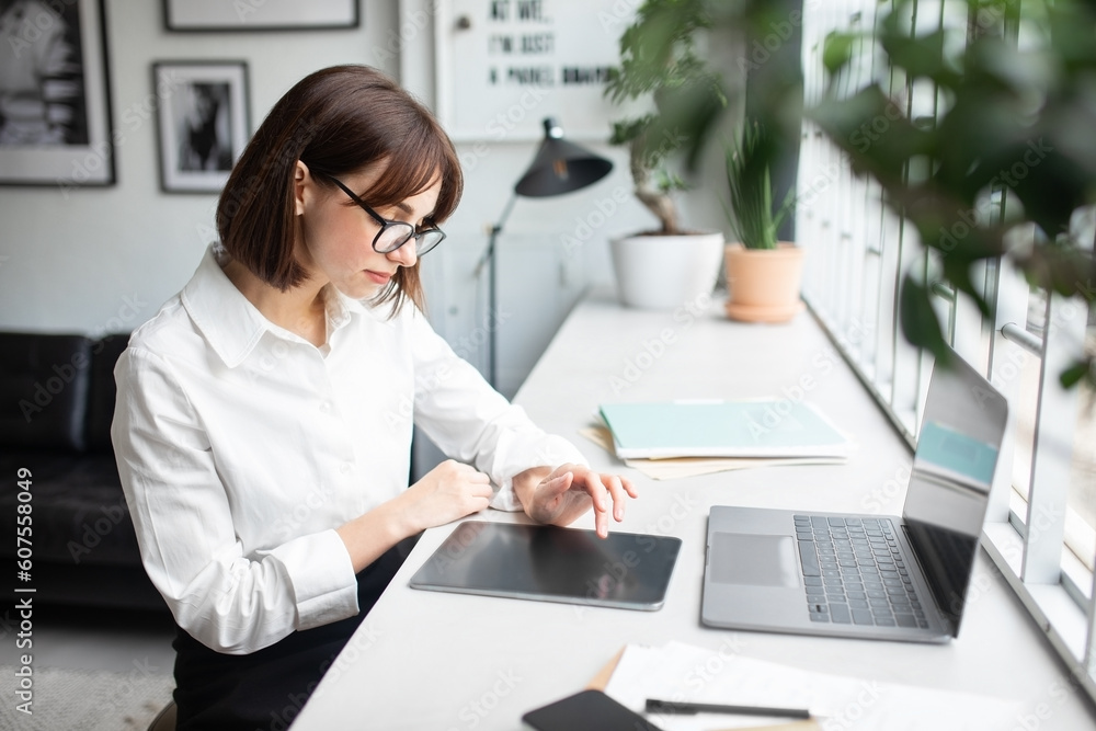 Young businesswoman sitting at table and using digital tablet with empty screen, working in cafe interior, free space Young businesswoman sitting at table and using digital tablet with empty screen, working in cafe interior, free space
