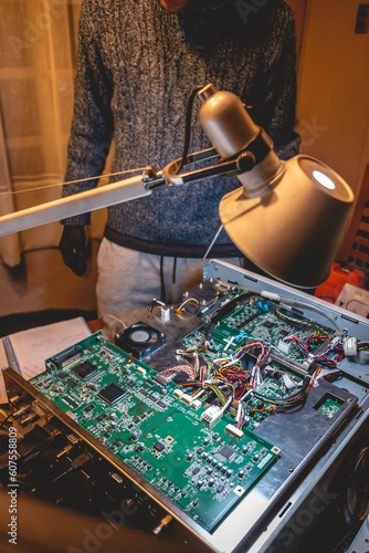 Electronics expertise: a young latino repairing an electronic equipment on a table photo