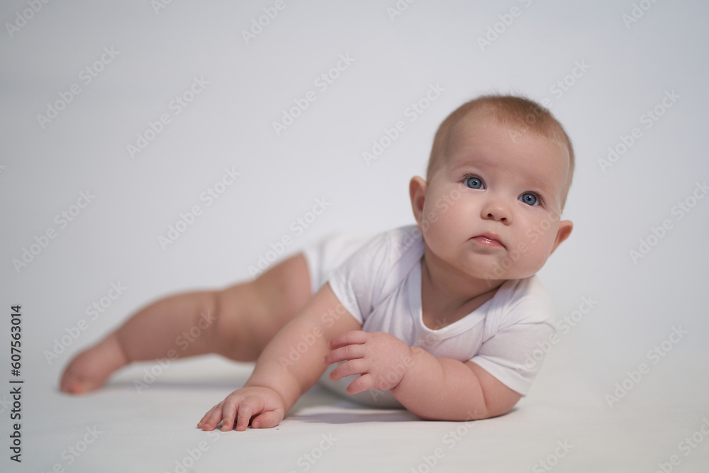 A newborn baby is trying to roll over on his stomach. photography on a light background A newborn baby is trying to roll over on his stomach. photography on a light background