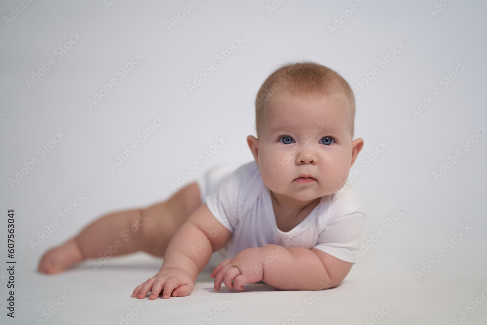 A newborn baby is trying to roll over on his stomach. photography on a light background A newborn baby is trying to roll over on his stomach. photography on a light background