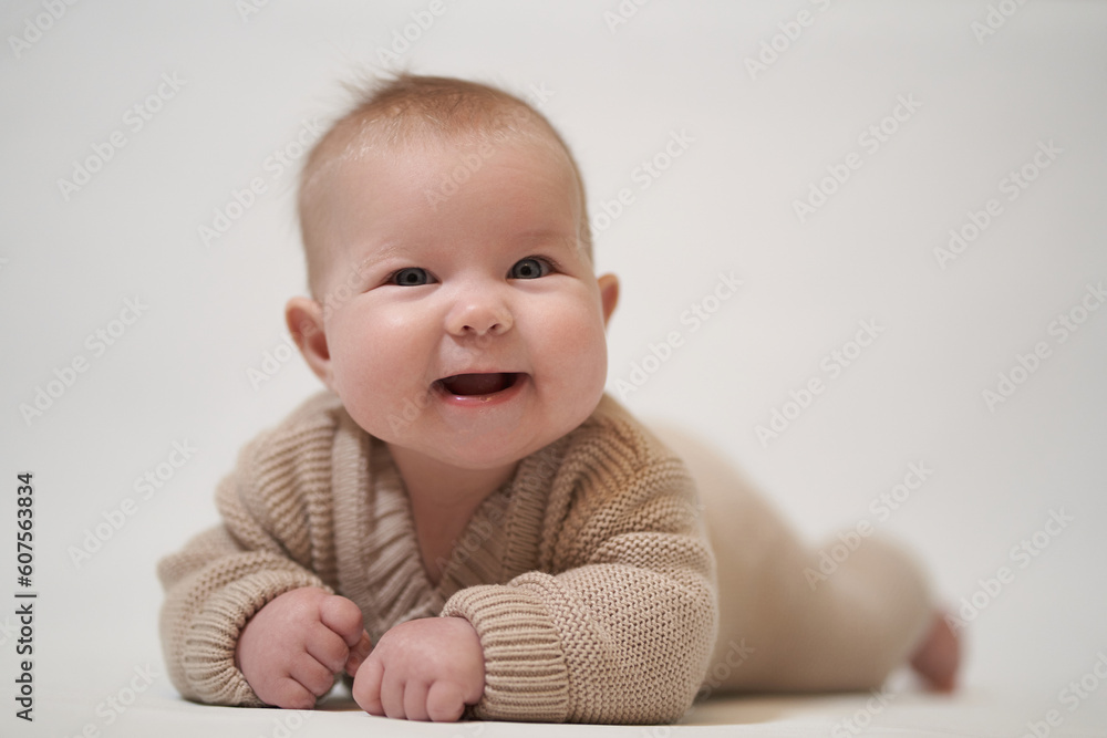 smiling baby in knitted clothes lies on his stomach smiling baby in knitted clothes lies on his stomach