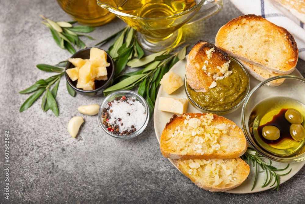 Ciabattas, olive oil in a bowl with olives, herbs, spices, garlic, pesto, parmesan and ciabatta bread on a texture background.Banner. Healthy food concept.Delicacy. Mediterranean Kitchen. Copy space. Ciabattas, olive oil in a bowl with olives, herbs, spices, garlic, pesto, parmesan and ciabatta bread on a texture background.Banner. Healthy food concept.Delicacy. Mediterranean Kitchen. Copy space.